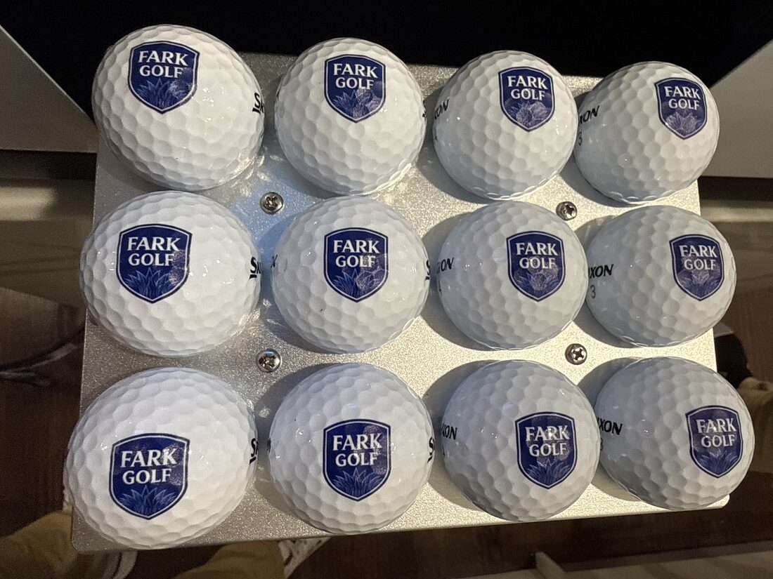 A dozen golf balls printed with the navy FARK Golf crest